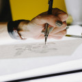 Main tenant un crayon en train de tracer un croquis sur une feuille blanche
